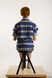 Sitting reference of whole body striped blue gray shirt blue jeans shorts black gray shoes Wesley